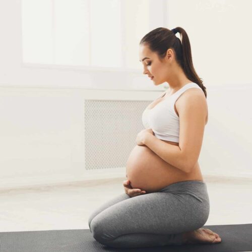 Pregnant woman training yoga in lotus pose